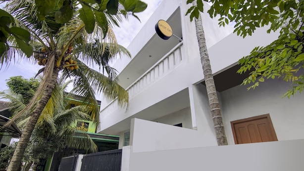 Un bâtiment moderne à deux étages, doté d’une façade blanche, d’un portail noir et d’une porte en bois.