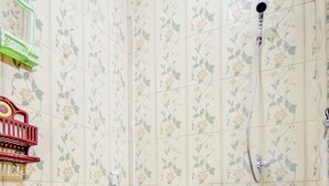 Une salle de bain équipée de toilettes, d’une douche et de carreaux décorés de motifs floraux.