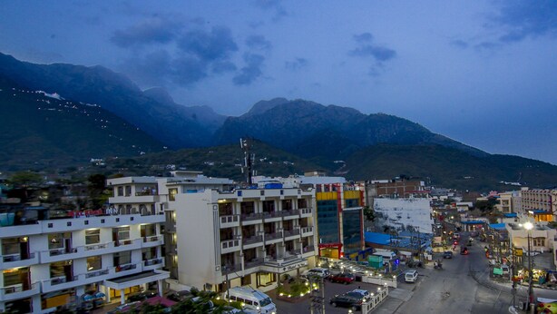 A multi-story hotel with balconies and a view of mountains in the background. - Itsy Hotels Satya Shree (Reasi)