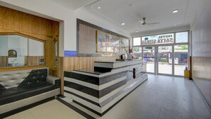 A reception area with a counter, seating, and a view of the outside. - Itsy Hotels Satya Shree (Reasi)