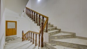 A marble staircase with wooden balusters leading to a landing. - Itsy Hotels Satya Shree (Reasi)
