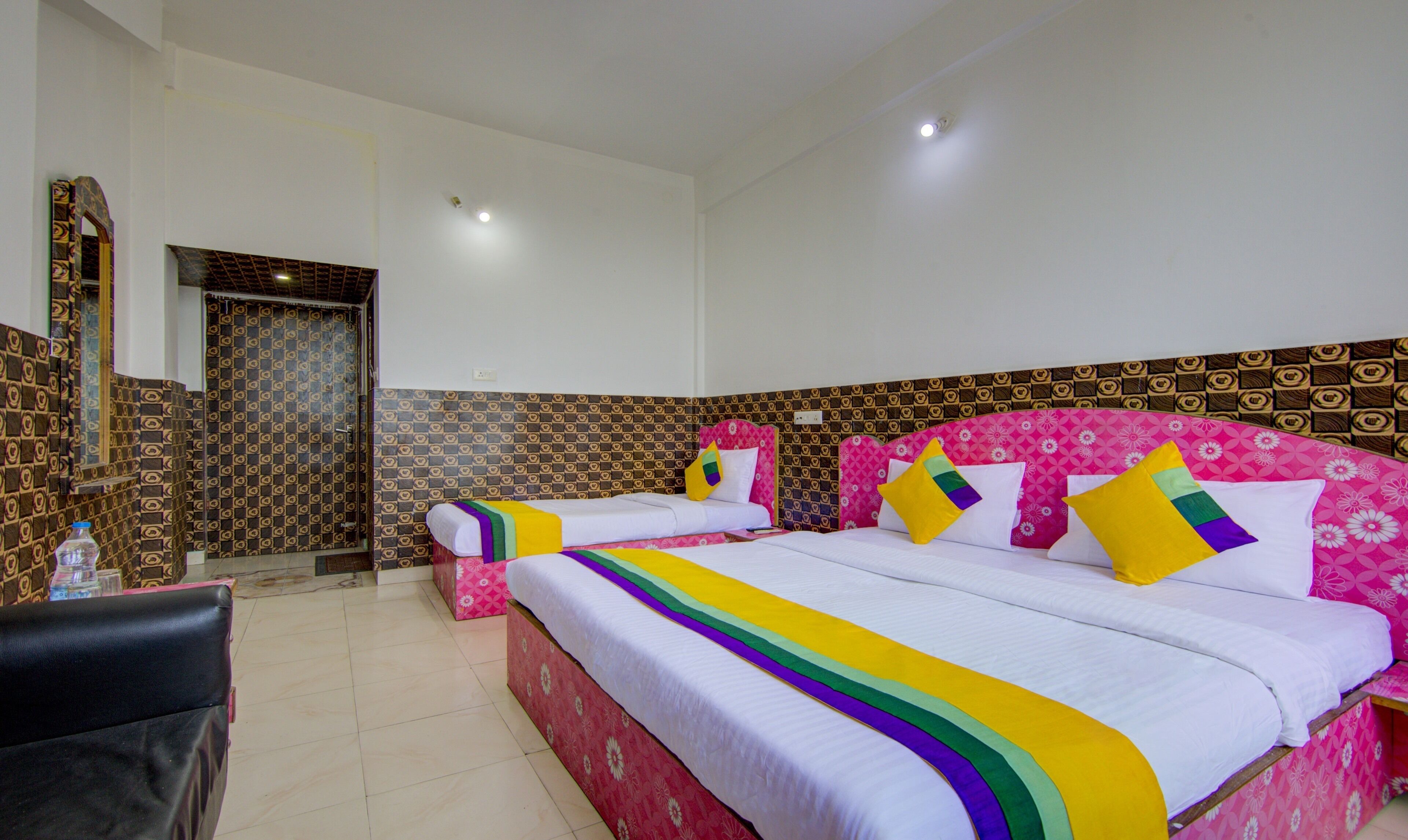 A hotel room with two beds, a bathroom, and a small seating area.