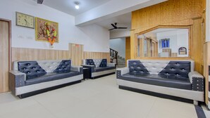 A reception area with two black and white sofas, a clock, and a framed picture on the wall. - Itsy Hotels Satya Shree (Reasi)