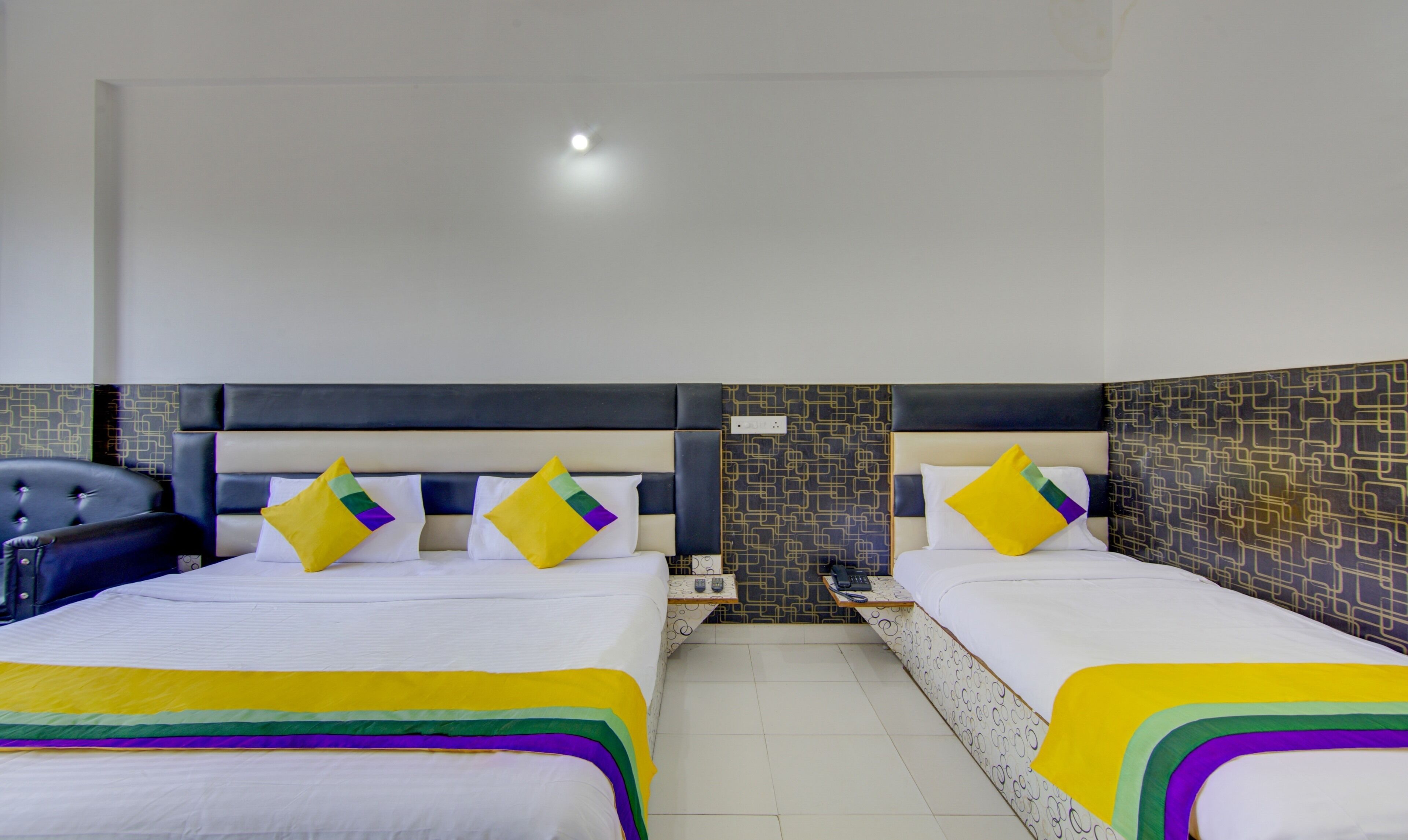 A hotel room with two beds, each with a headboard, a nightstand, and a chair.