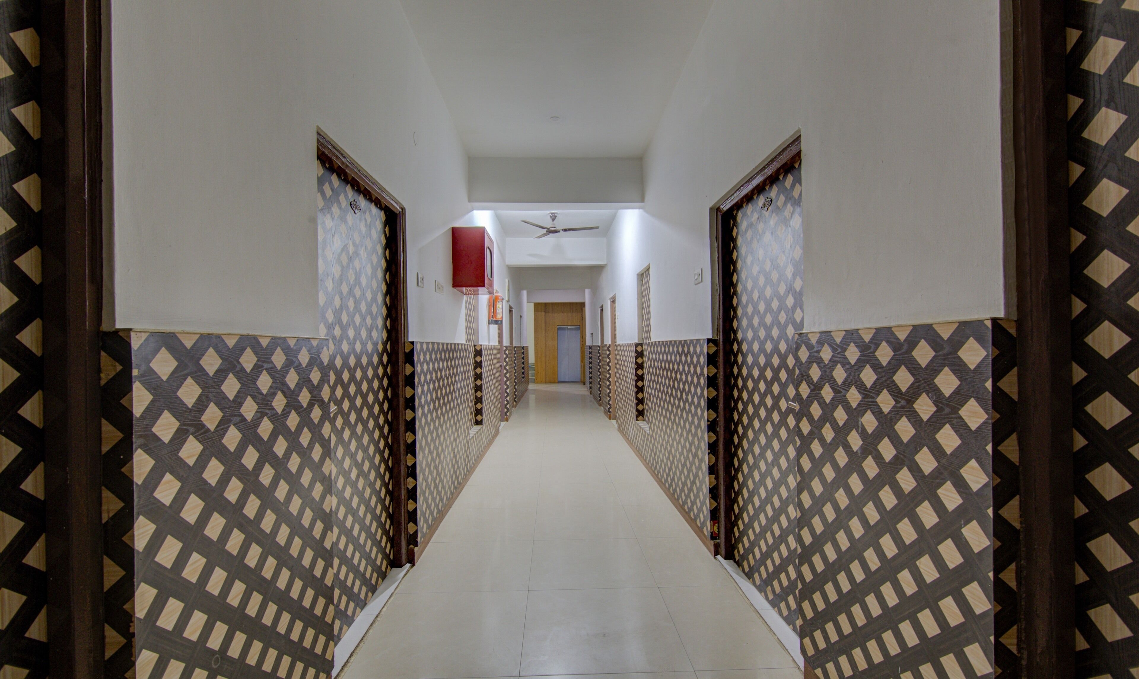 Um corredor com paredes estampadas e um ventilador de teto.