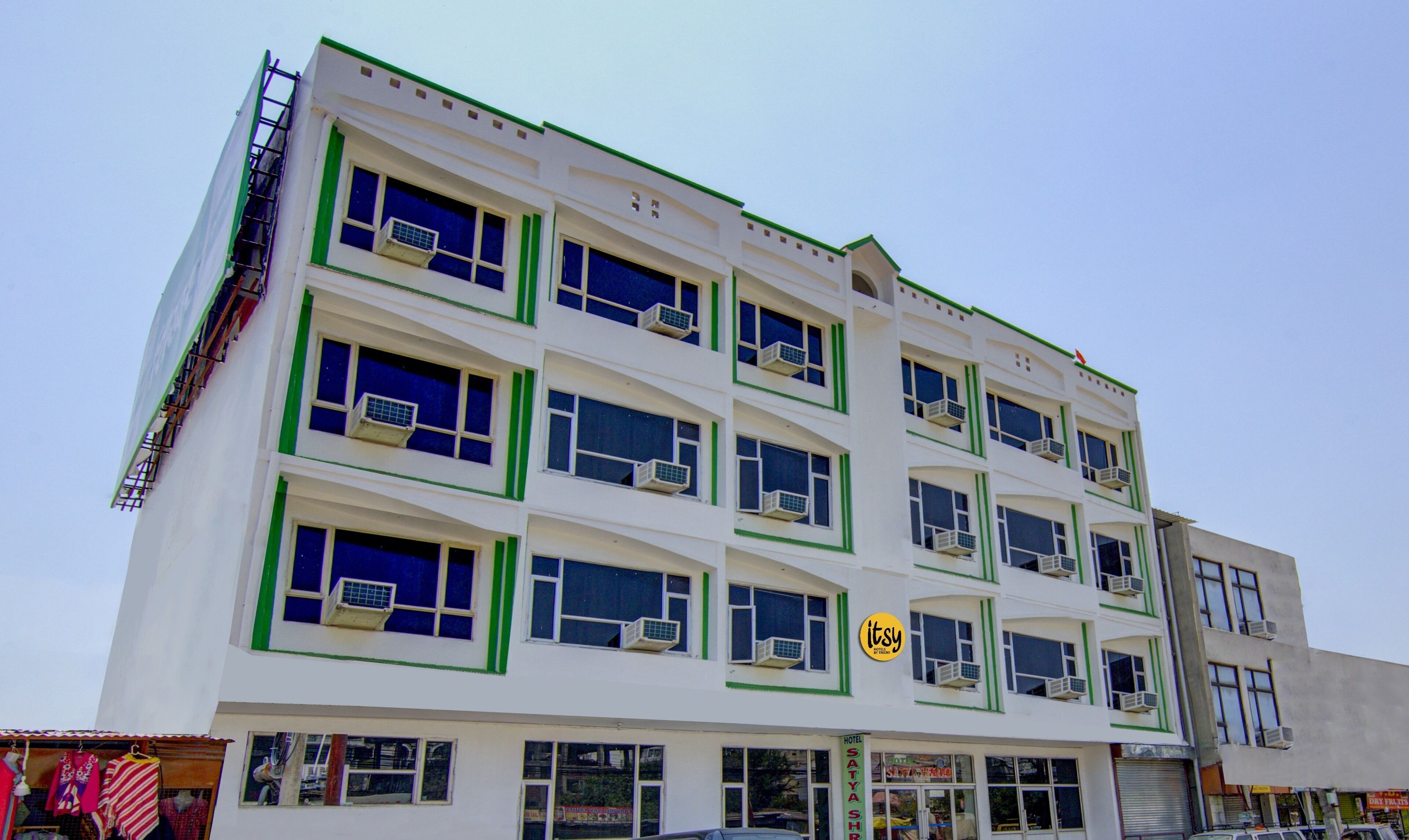 A multi-story hotel with air conditioning units on each window, a visible sign for 'Hotel Satya Sharma', and a 'LTSY' logo.