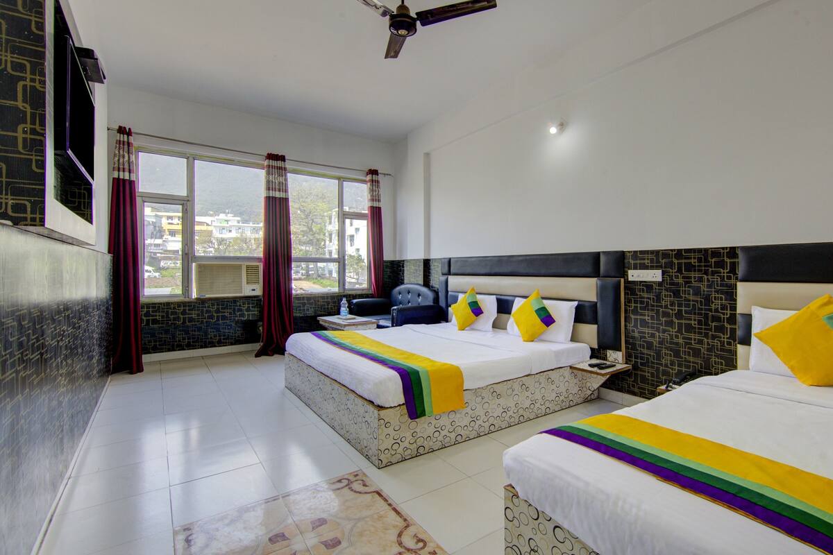 Habitación de hotel con dos camas, un ventanal grande y un ventilador de techo.