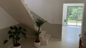 A staircase with white steps leading to a glass door. There are two potted plants on the floor beside the staircase.