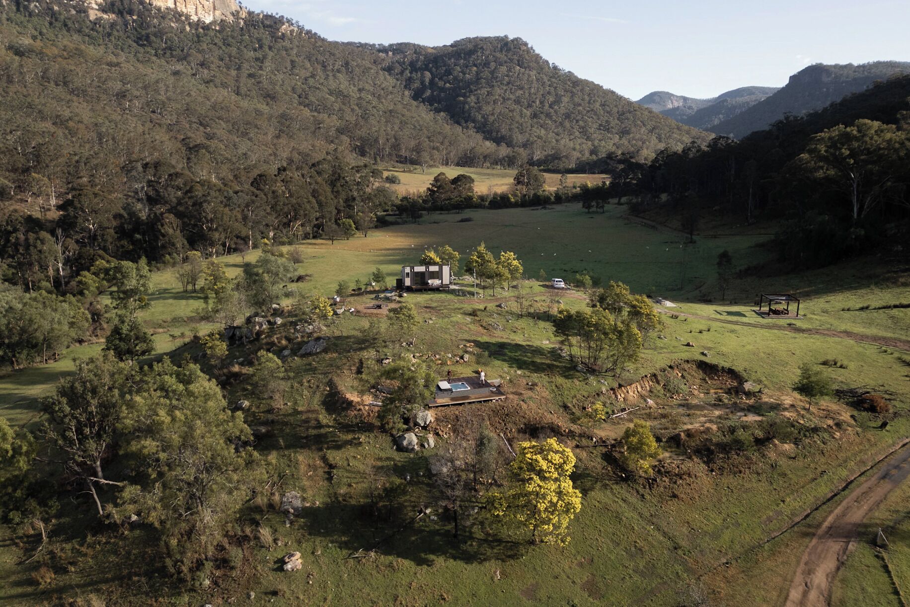 A rural landscape with a small cabin surrounded by fields and trees.