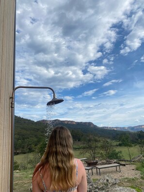 A person standing by a shower with a view of a mountainous landscape. - Modern cabin offering incredible views with fire pit, spa and hiking trails. (Upper Nile)