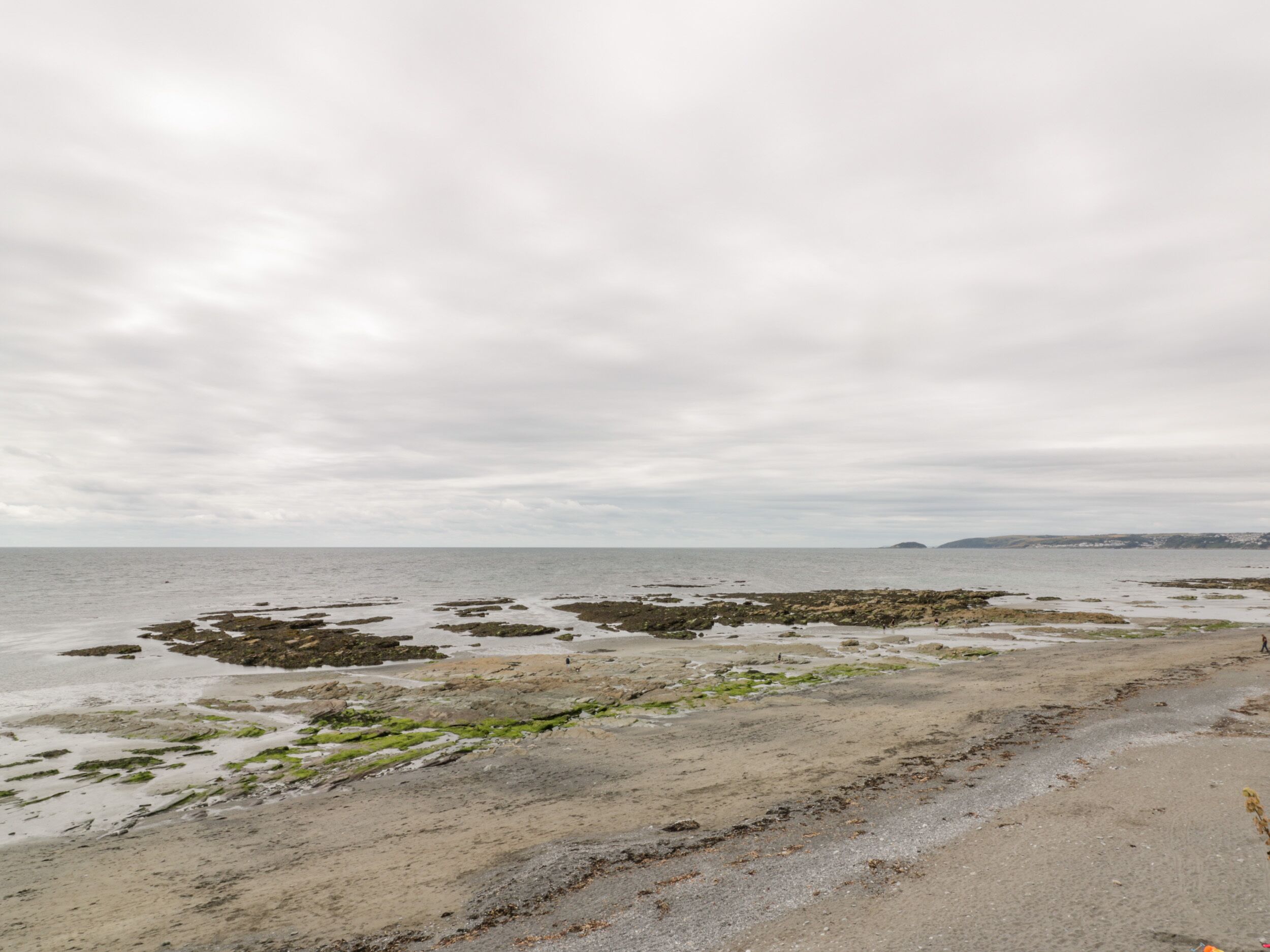A coastal landscape with rocky formations and a sandy beach.