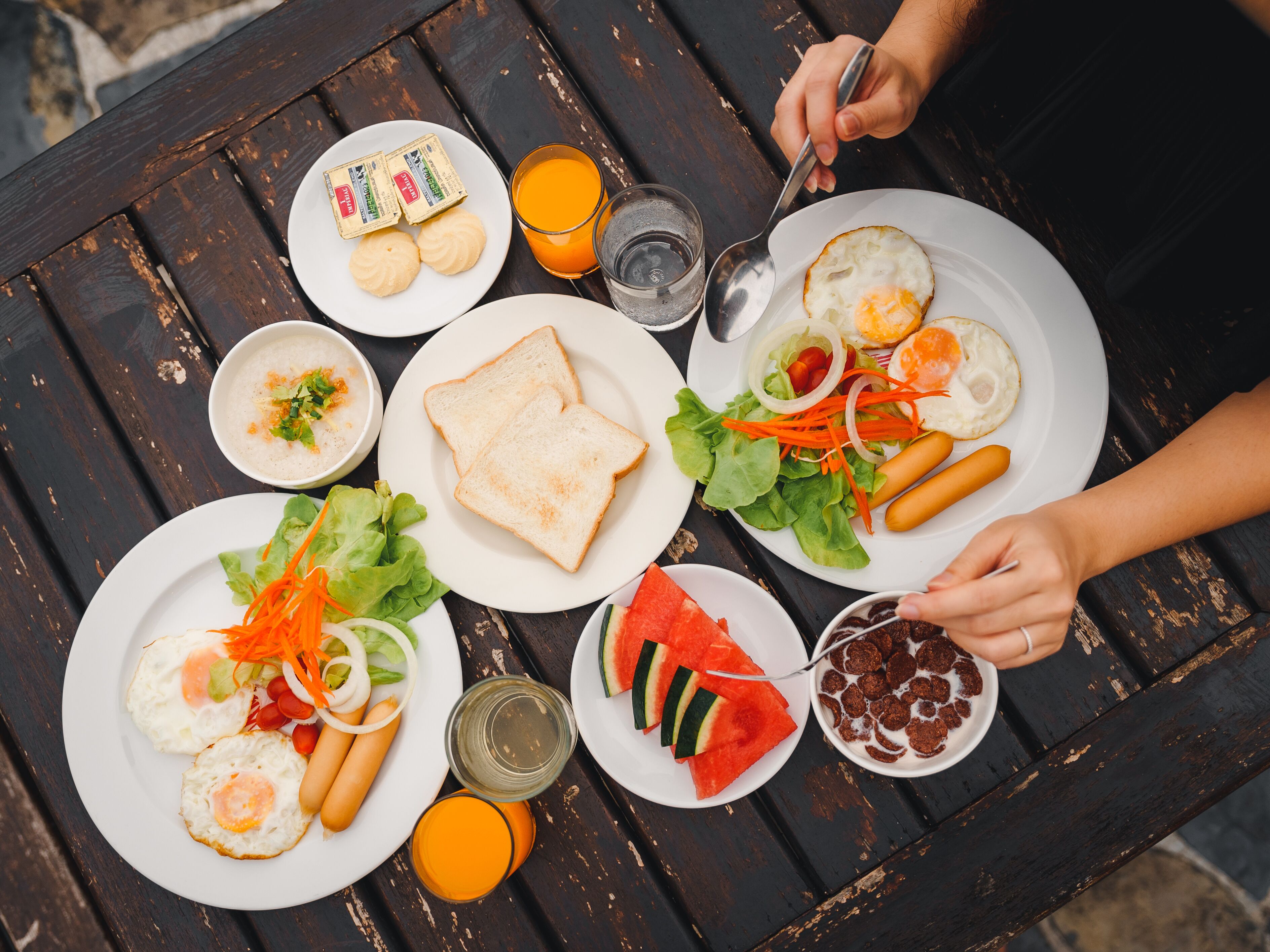 Uma mesa com diversos alimentos, incluindo ovos, cachorros-quentes e fatias de melancia.