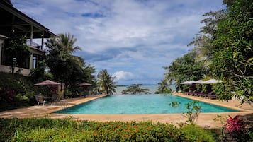Una piscina al aire libre, sillones reclinables de piscina
