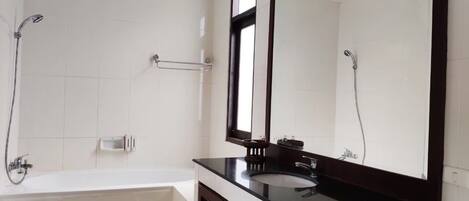 Un baño moderno con una bañera, un espejo grande y una ducha.
