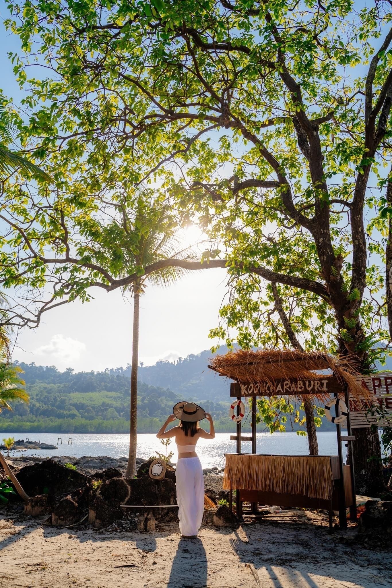 A beach scene with a sign reading "KONCARABURI" and a thatched structure.