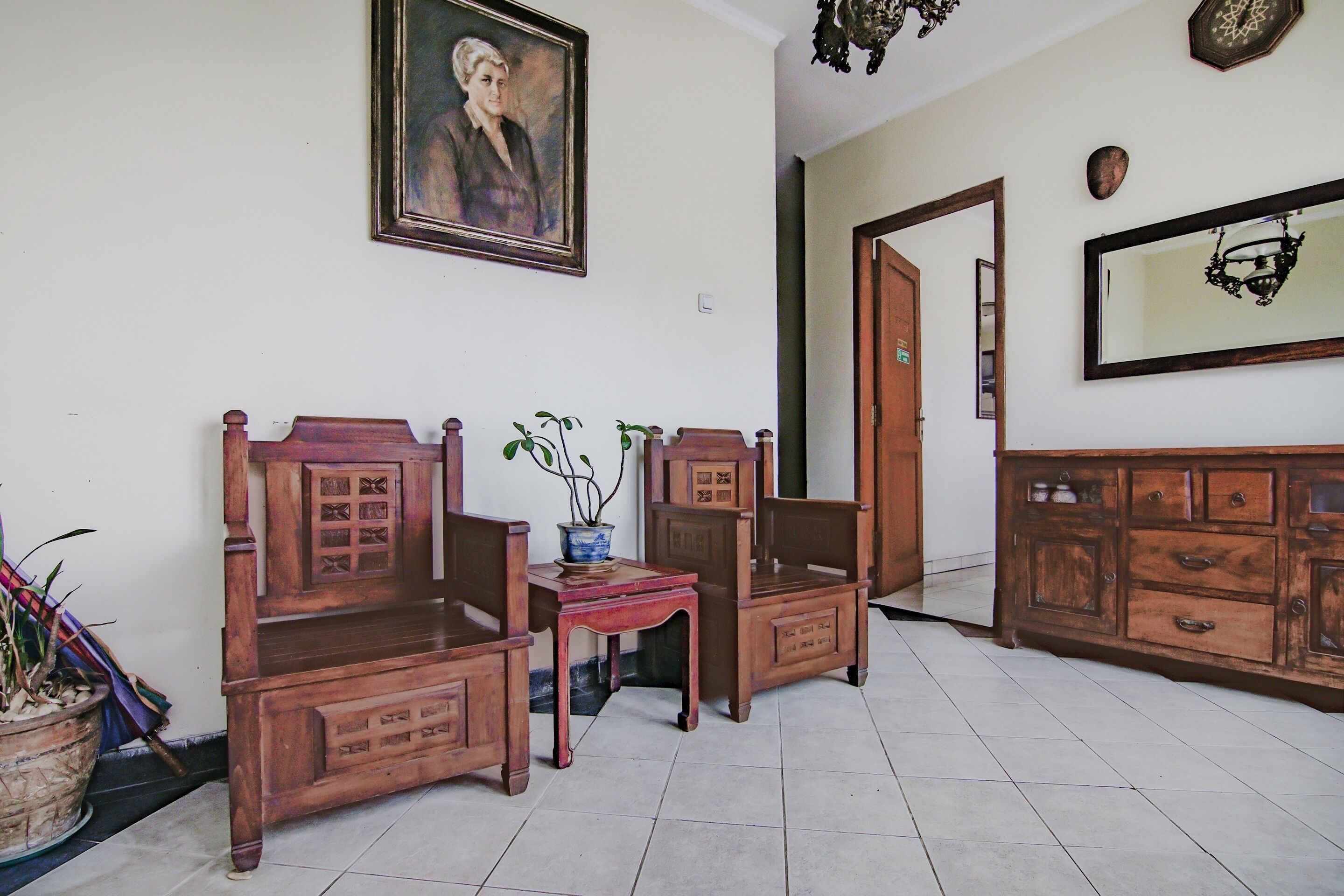 A room with a wooden sofa set, a small table with a potted plant, and a cabinet with drawers.