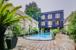 A courtyard with a swimming pool, surrounded by potted plants and a modern building with large windows. - Hotel O Gayatri Residence (Jakarta)