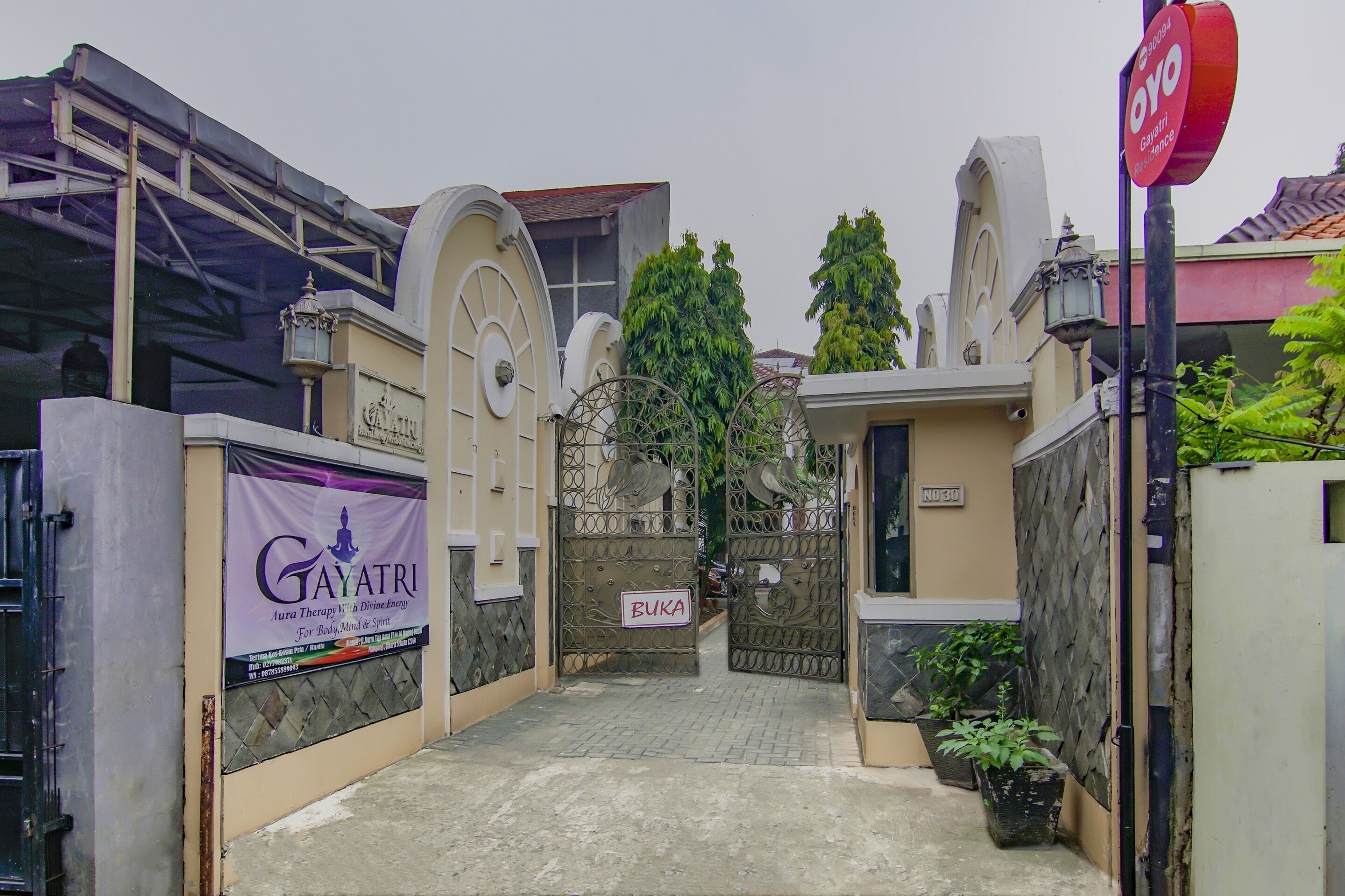 A gated entrance with a sign for 'Gayatri' and a 'Buka' sign, indicating a private or restricted area.