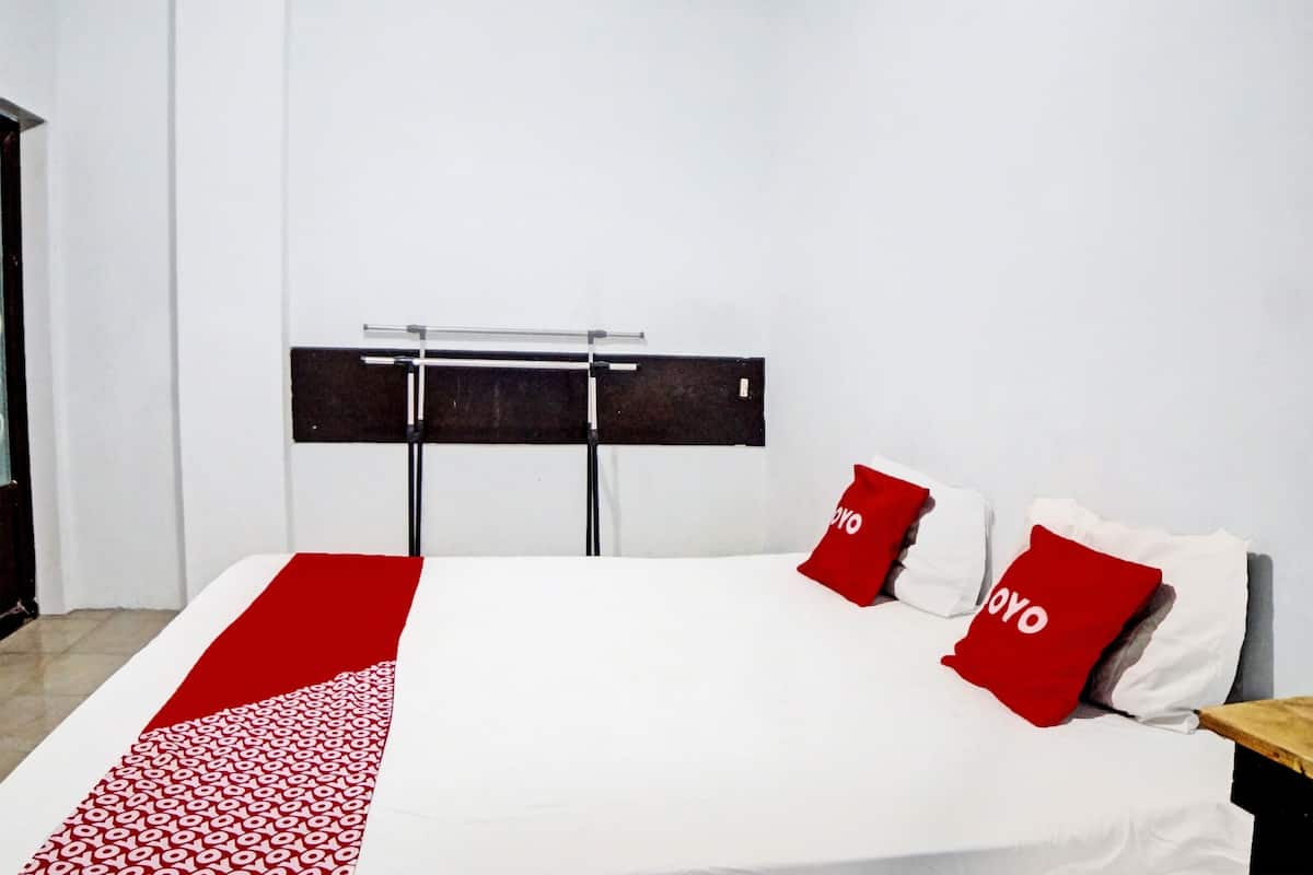 A hotel room with a bed, a red and white patterned runner, and two red pillows with the word "YOYO" on them.