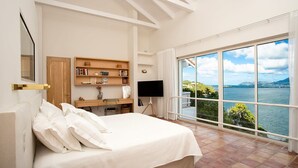 Une chambre avec un grand lit, un bureau, une télévision et une vue sur un lac.