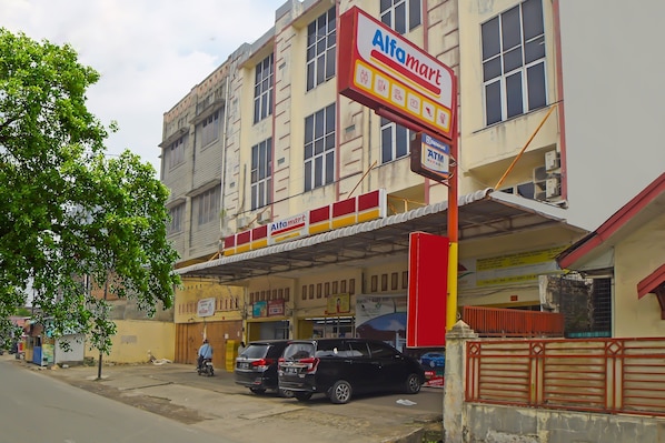 A multi-story building with a prominent Alfamart sign, a covered parking area, and a gated entrance. - OYO 92371 Bb House Japaris (Medan)