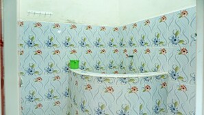 Ein Badezimmer mit Fliesen mit Blumenmuster, einer grünen Mülltonne und einem weißen Waschbecken.