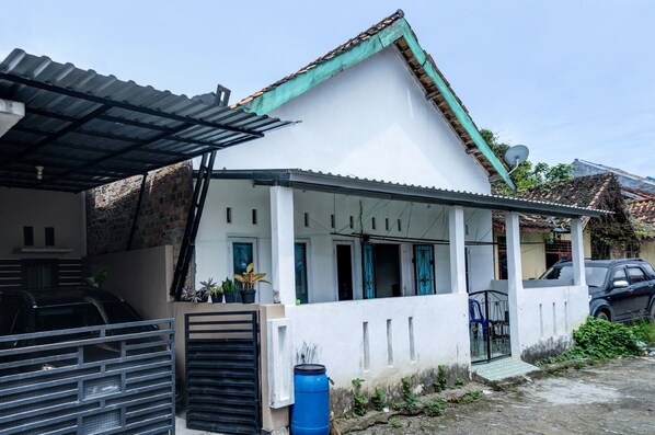 A white house with a green roof, a covered porch, and a satellite dish. - Hotel O Penginapan Indola Near Masjid Al Muhtadin (Muaradua)