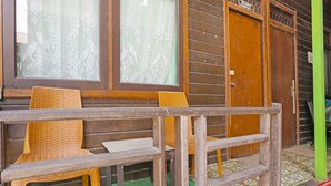 Een houten gebouw met een veranda, voorzien van rieten stoelen en een houten leuning.