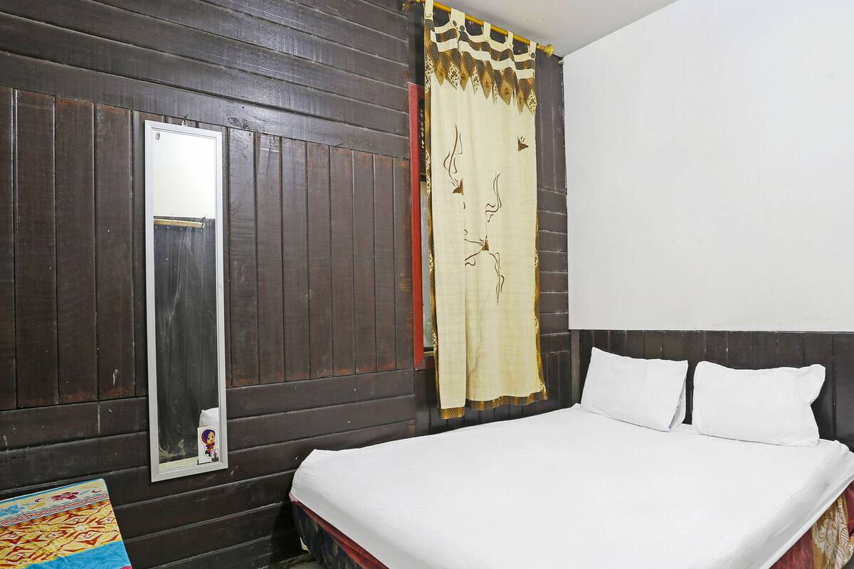Un dormitorio con cama, espejo y cortina.