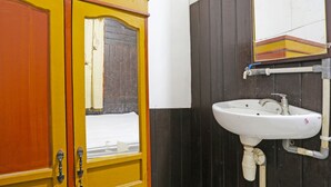 Een badkamer met een gele deur, een wastafel en een spiegel.