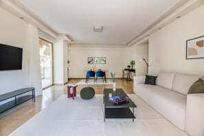 Un salon moderne doté d’un téléviseur à écran plat, d’un canapé, d’une table basse et d’un coin repas avec des chaises et une table.