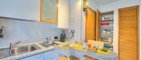 Una cocina con un lavamanos, dos taburetes, una mesa de madera y una puerta de madera.