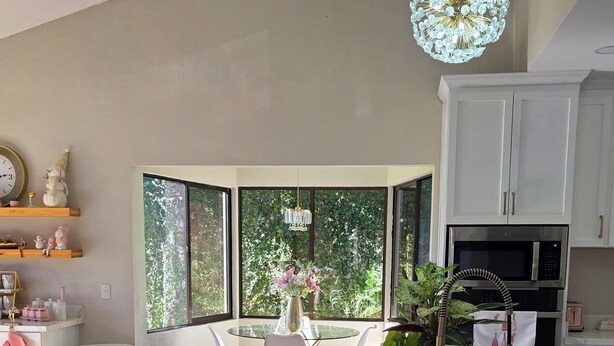 A modern kitchen with a marble countertop, a built-in oven, and a large window overlooking greenery. - Beautiful and cozy home in a safe and private environment (Alajuela)