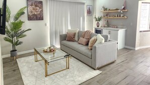 A modern living room with a grey sofa, a glass coffee table, and a potted plant. - Beautiful and cozy home in a safe and private environment (Alajuela)