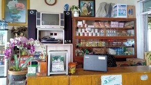 A small shop with a wooden counter, a television, a clock, and shelves stocked with canned goods and other items. - OYO Life 3020 Penginapan Citra Rasa (Plaosan)