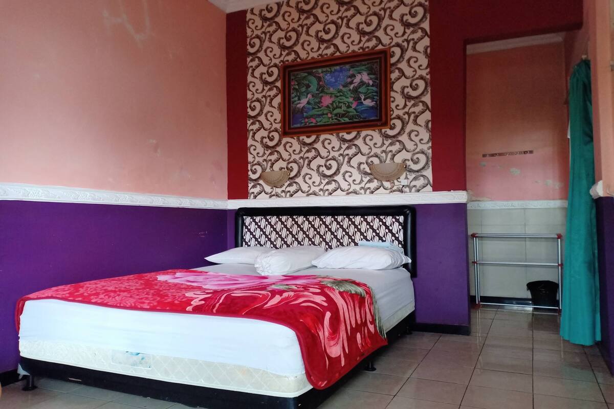 Ein Zimmer mit einem Bett, violetten Wänden, einer Wanddekoration mit Muster und einer Tür im Hintergrund.