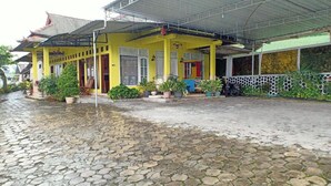 A yellow building with a covered porch and potted plants. - OYO Life 3020 Penginapan Citra Rasa (Plaosan)