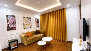 A modern living room with a sofa, two small tables, and a television.