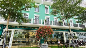 The exterior of the Jade Ha Long Hotel with a green facade, a balcony with railings, and a flower pot with red flowers. - JADE HA LONG HOTEL (Bai Chay)