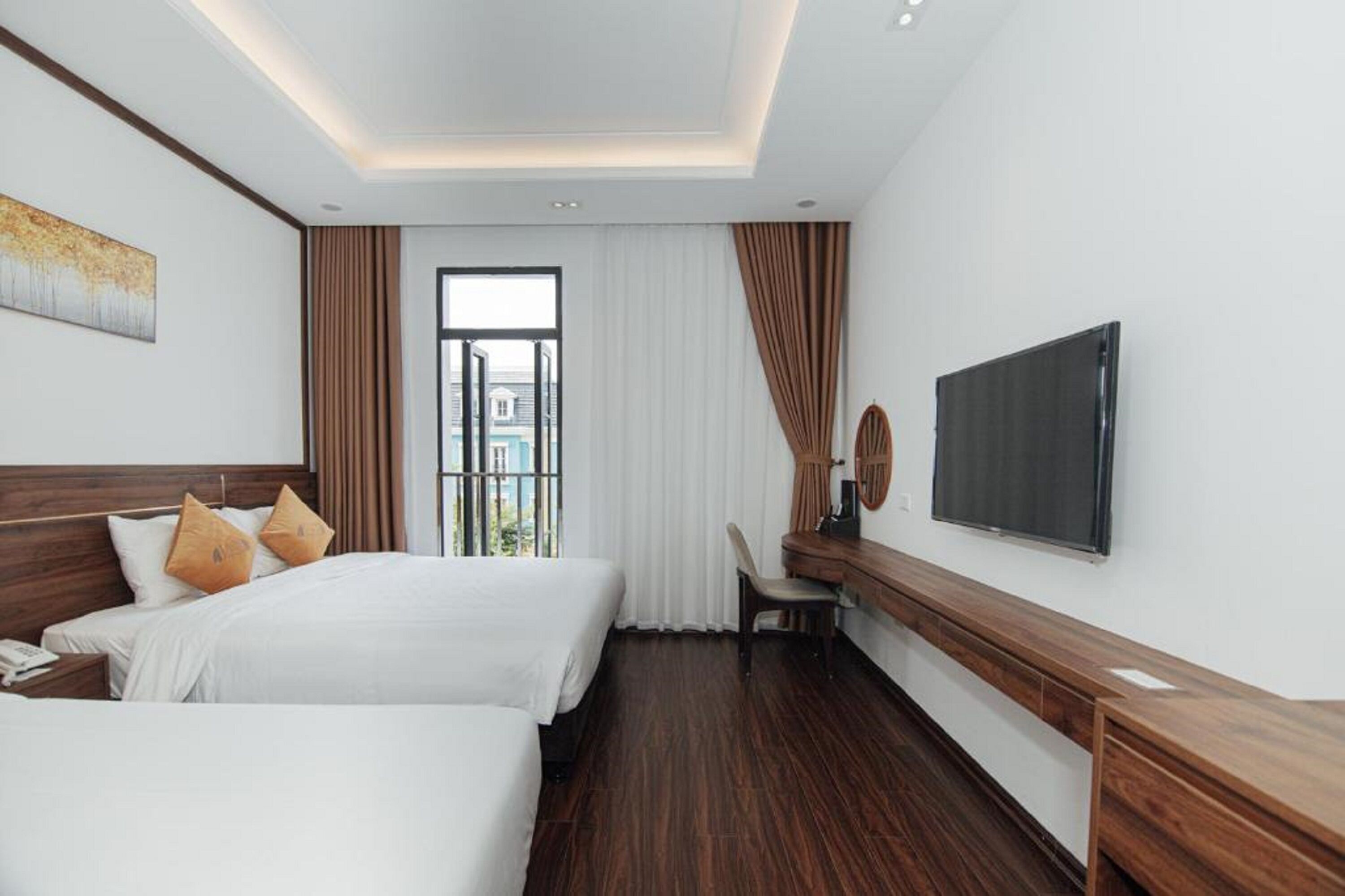 A hotel room with two beds, a desk, a flat-screen TV, and a window with curtains.