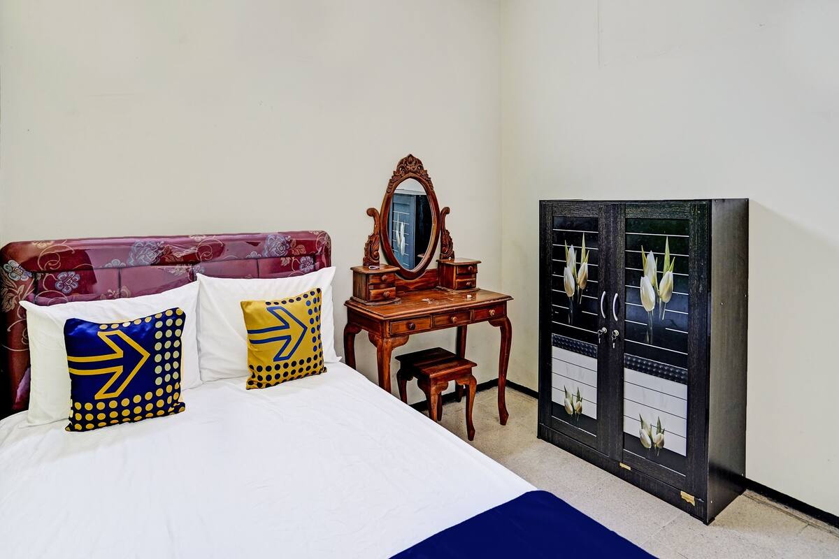 Un dormitorio con cama, cómoda con espejo y armario.