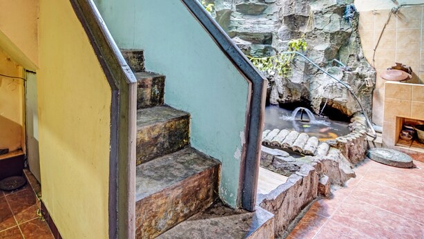 A staircase leading to a stone-walled area with a small water feature.