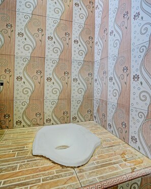 A bathroom with a tiled floor and walls featuring floral and swirl patterns. - SPOT ON 91716 Kost Yy Syariah (Mojokerto)
