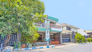 A two-story building with a balcony, a signboard, and a gated entrance.