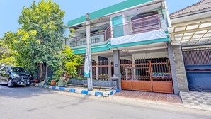 A two-story building with a balcony, a gated entrance, and a parked car.