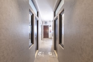 A hallway with doors on both sides, a ceiling fan, and a light fixture.