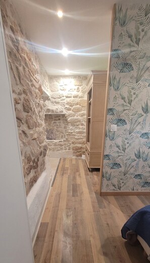A narrow hallway with stone walls, wooden flooring, and a cabinet. - Gîte Provence Piscine Luberon - Domaine ARTEMISS (APT)