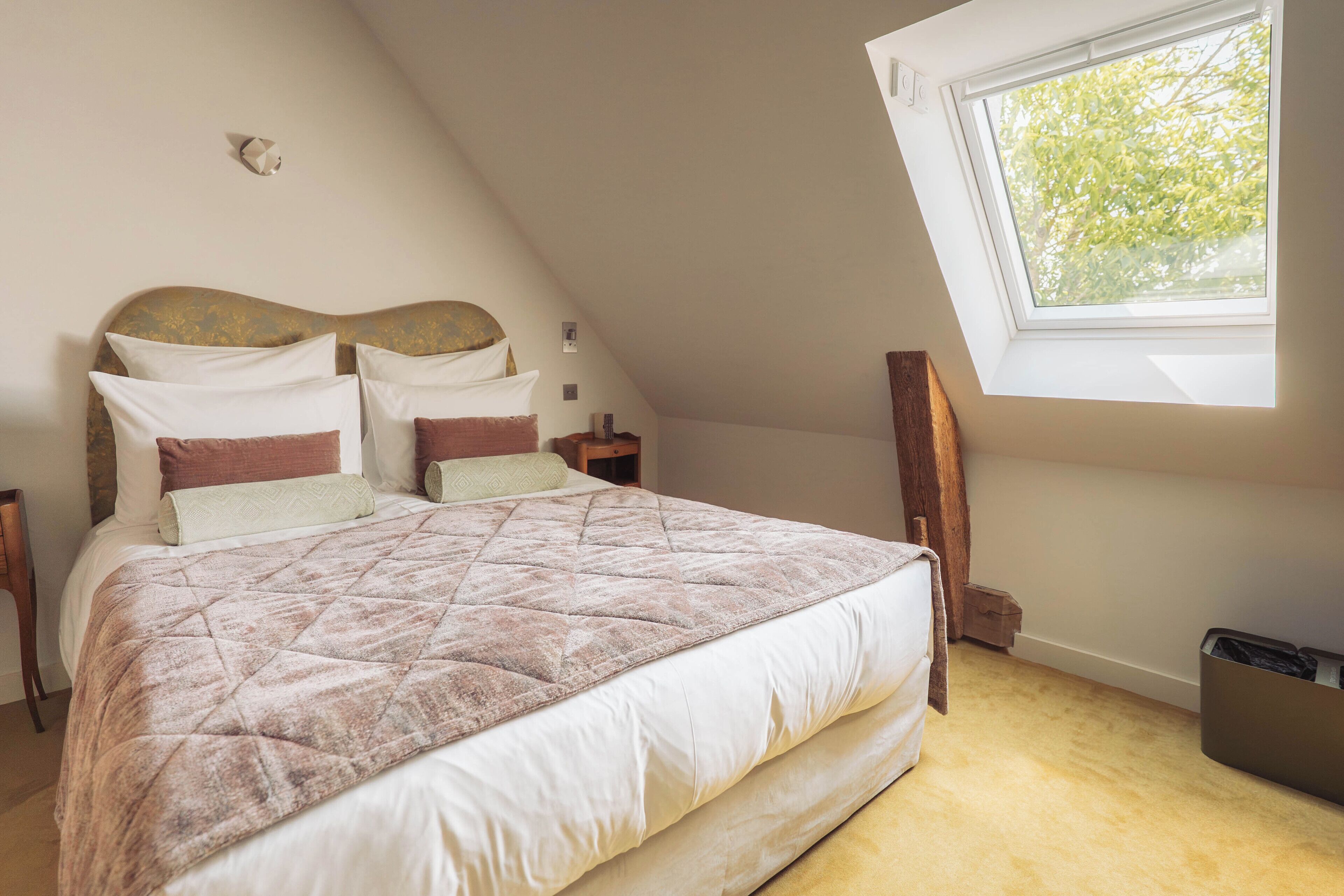 A bedroom with a bed, nightstands, a window, and a wall-mounted light fixture.