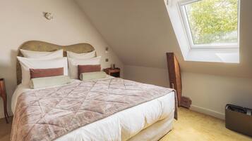 A bedroom with a bed, nightstands, a window, and a wall-mounted light fixture.