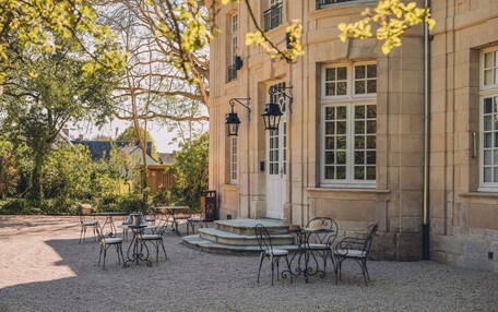 A courtyard with outdoor seating and a building with stone walls and windows.